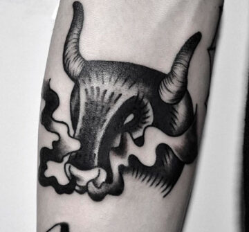 Черная татуировка головы быка на предплечье
