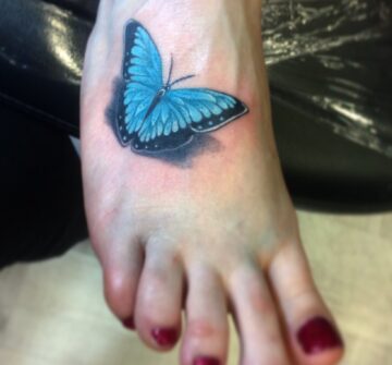 Синяя бабочка на ступне у девушки