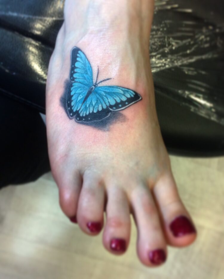 Синяя бабочка на ступне у девушки