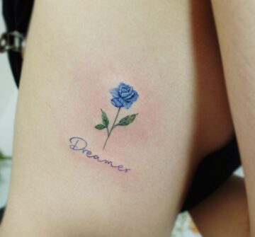 Маленькая синяя роза и надпись, тату на боку у девушки