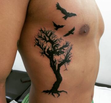 Черное дерево с птицами, тату на ребрах у парня