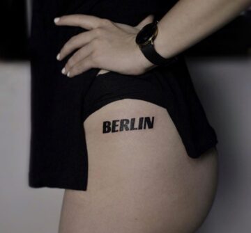 BERLIN, тату надпись на бедре у девушки