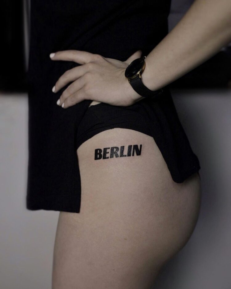 BERLIN, тату надпись на бедре у девушки