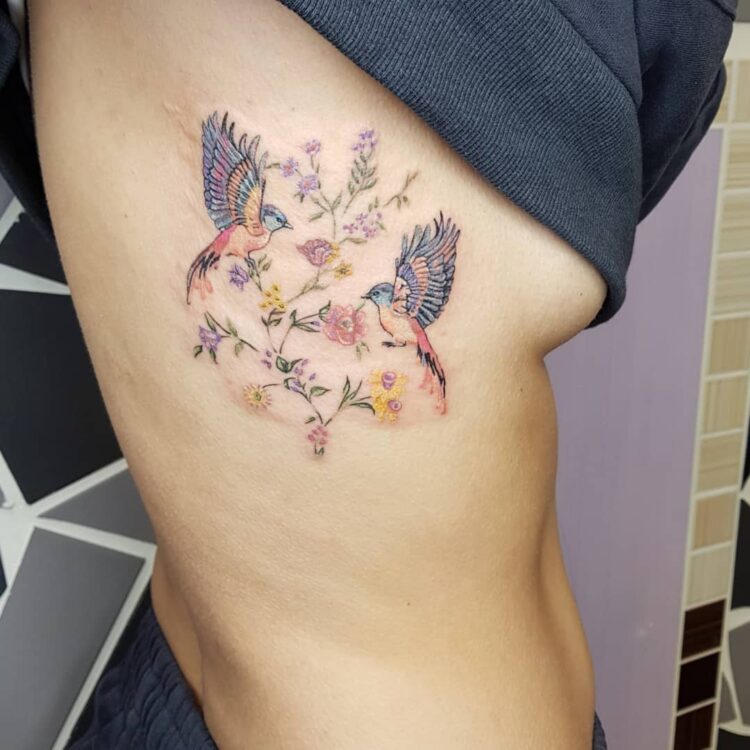 Две птицы среди цветов, тату на ребрах у девушки