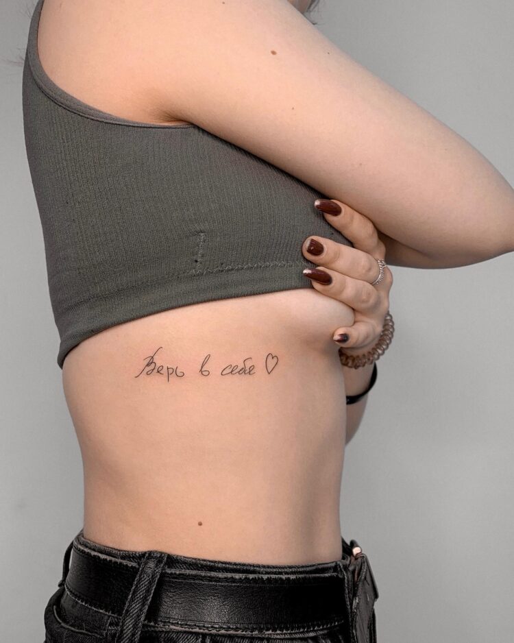 Надпись «Верь в себя» и сердечко, тату на ребрах у девушки